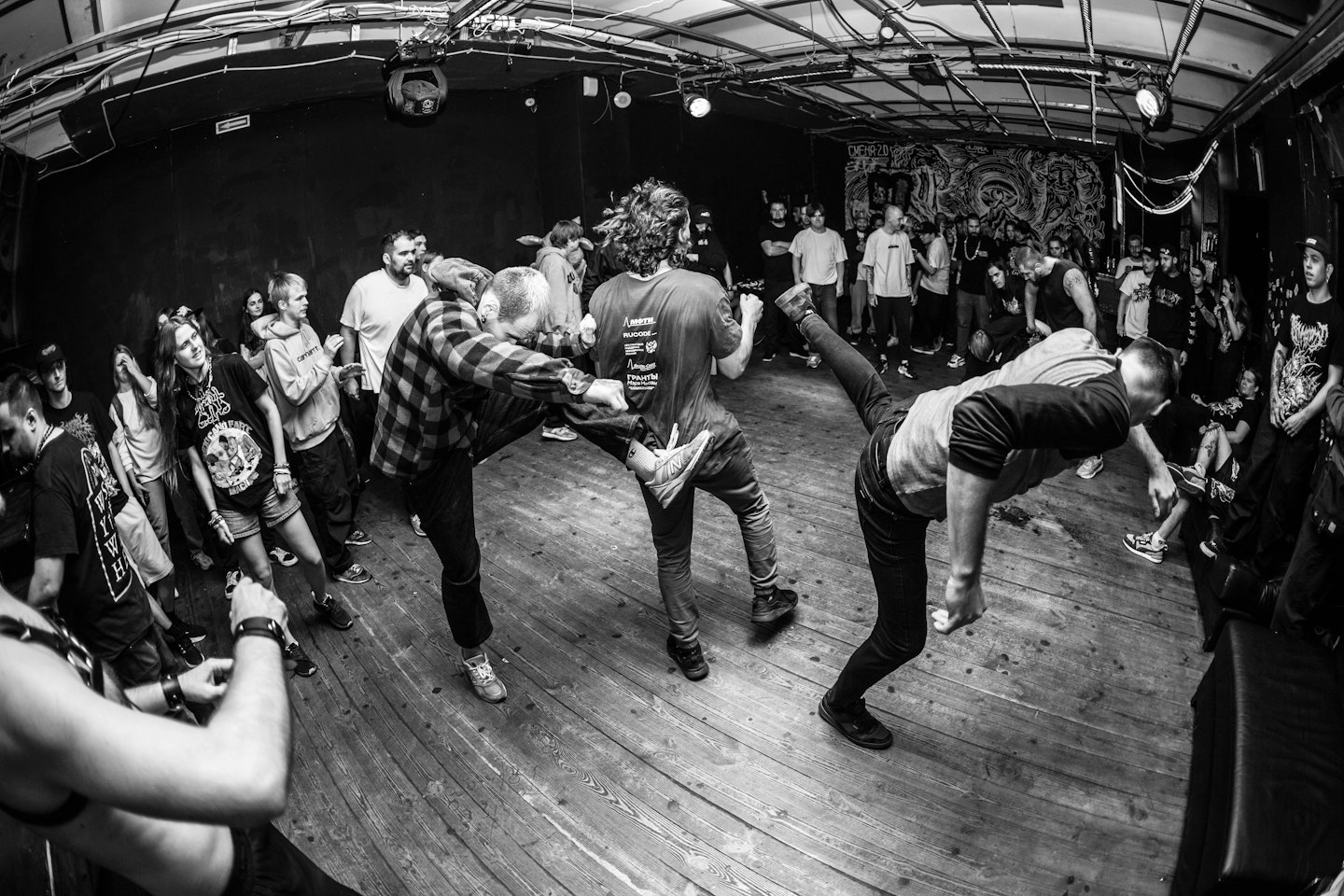 Konzertbesucher tanzen ausgelassen im Moshpit in einer Indoor-Location.
