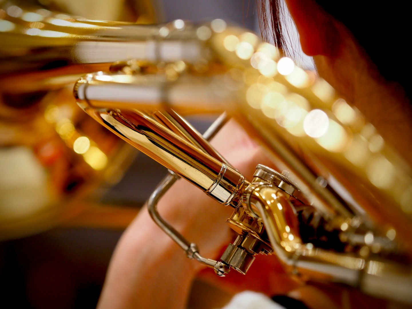 Ein Musiker spielt ein poliertes gold- und silberfarbenes Blechblasinstrument.