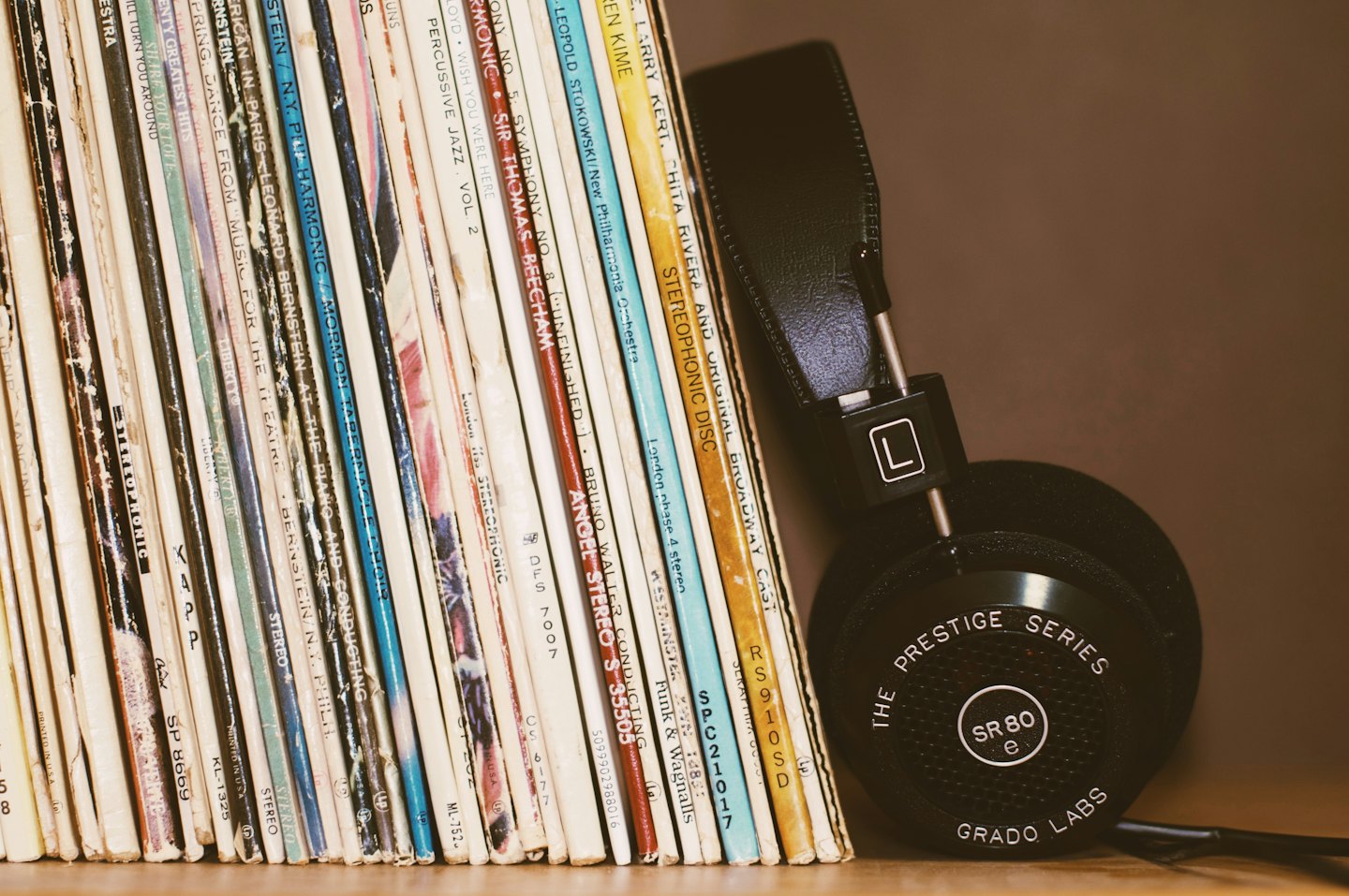 Stapel alter Schallplatten mit Kopfhörern auf einem Holzregal.