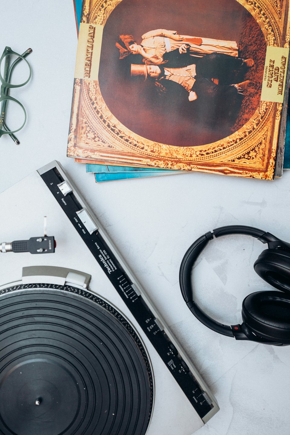 Plattenspieler, Kopfhörer und Schallplatten auf grauem Untergrund.